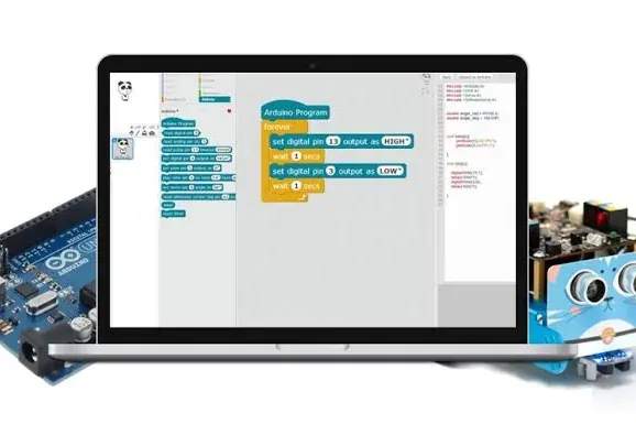 Portátil con el editor de bloques de mBlock abierto sobre un programa de Arduino, entre una placa Arduino Uno y un pequeño robot azul con sensor ultrasónico