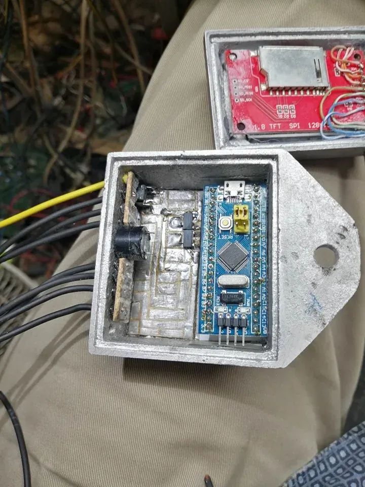 Caja de aluminio fundido abierta con la placa dentro: una STM32 Blue Pill azul a la derecha y, a su izquierda, los componentes de la etapa de entrada y potencia recubiertos de resina transparente