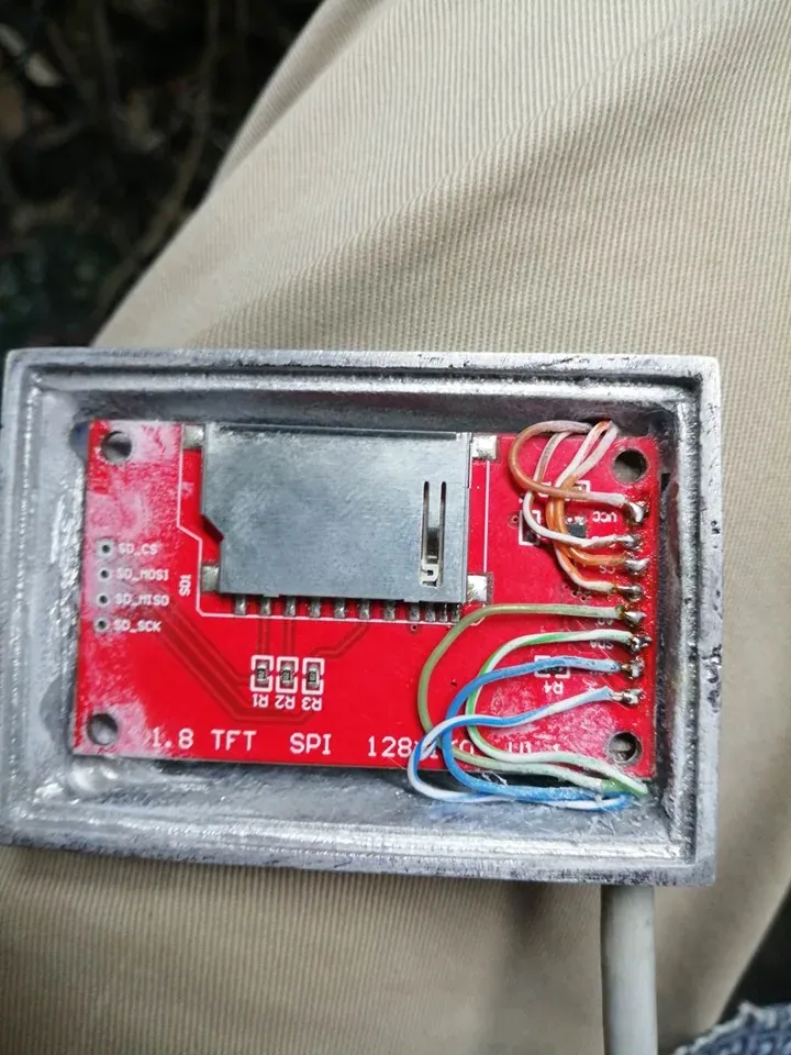 Parte trasera de la carcasa de aluminio de la pantalla con la placa roja del TFT de 1,8 pulgadas dentro, soldada a seis cables de colores por su hilera de pines
